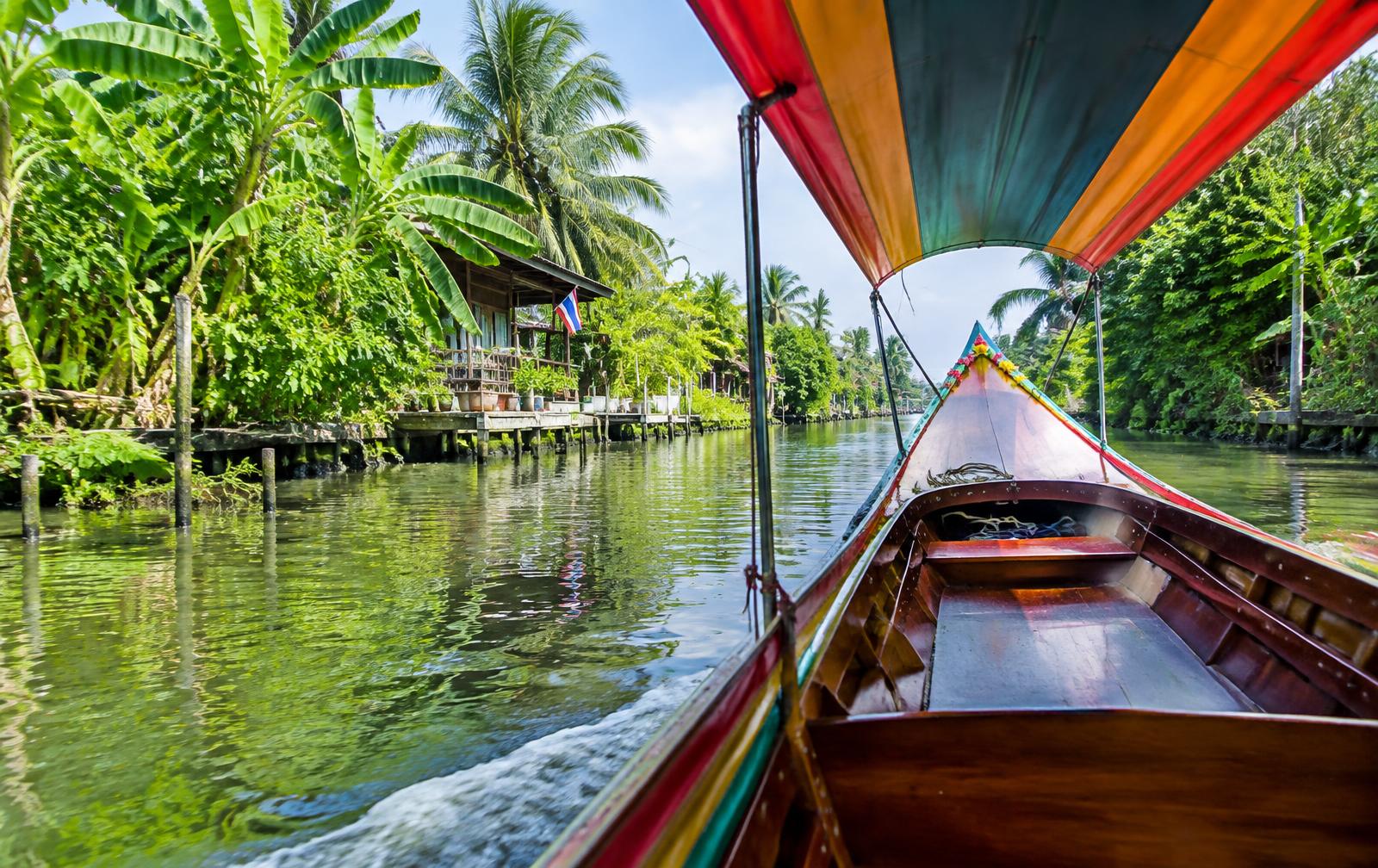 Barque à longue queue sur un canal verdoyant près de Bangkok