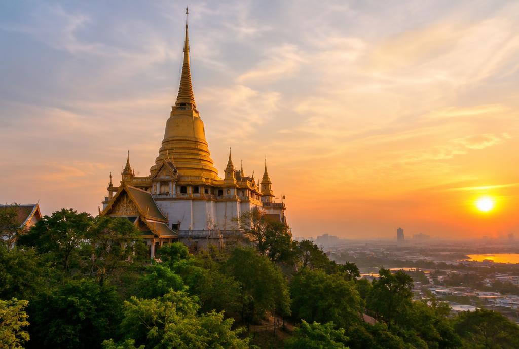 Grand chedi doré dominant la ville au coucher du soleil