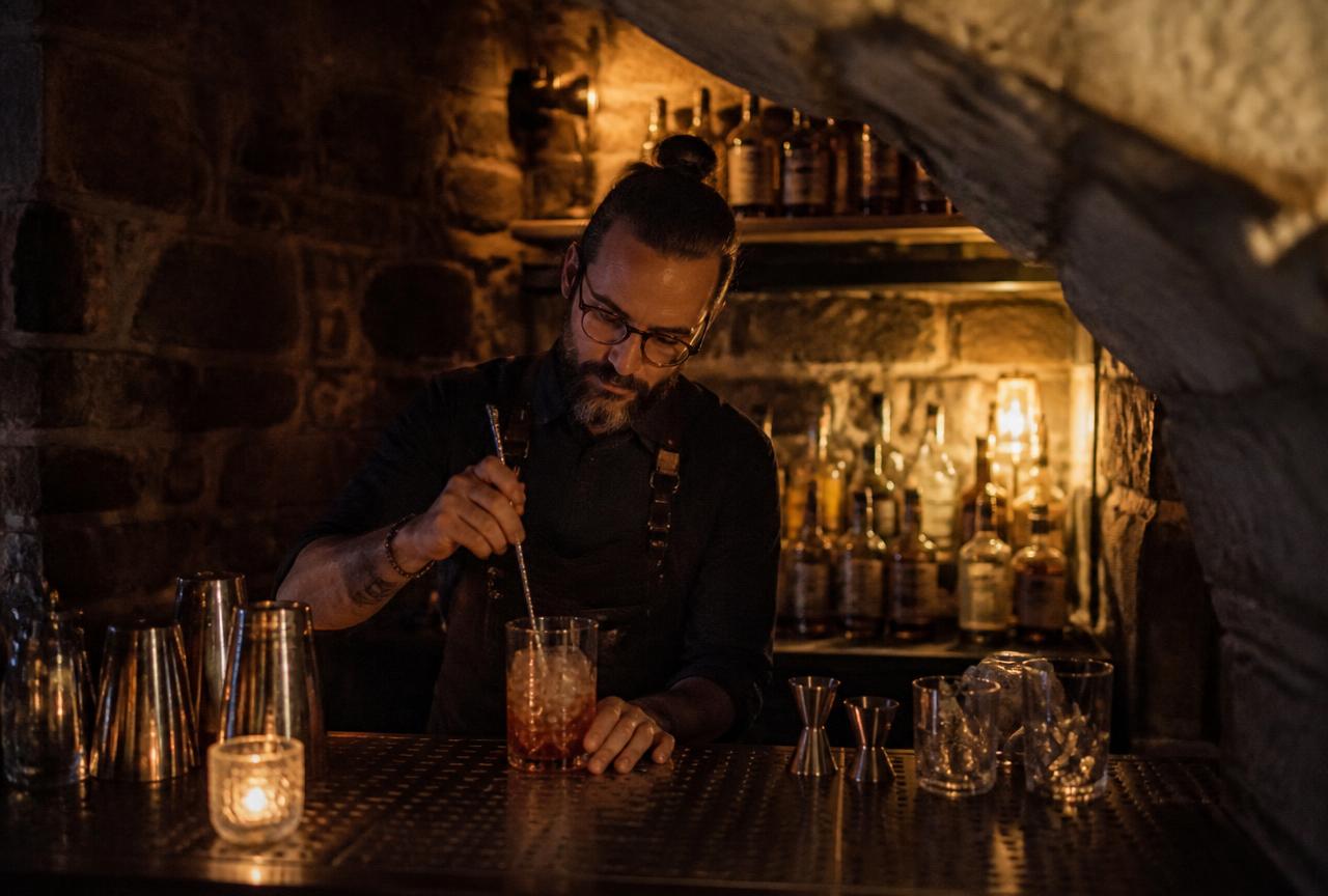 Barman préparant un cocktail dans un bar voûté de Québec
